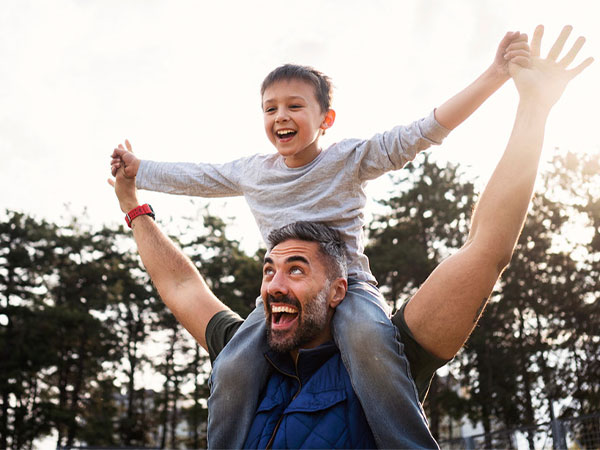 a father with his son on his shoulders smiling outside