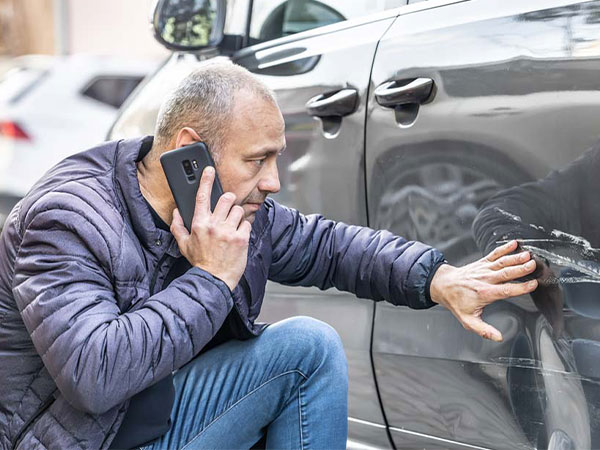 A person assessing the damage from a car crash